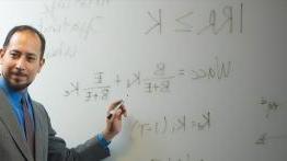 Professor teaching at a whiteboard facing a class