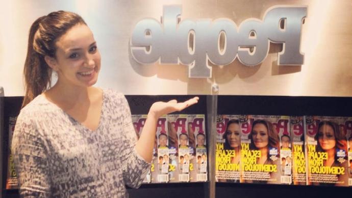 Rose Minutaglio poses for a photo in front of a People magazine display