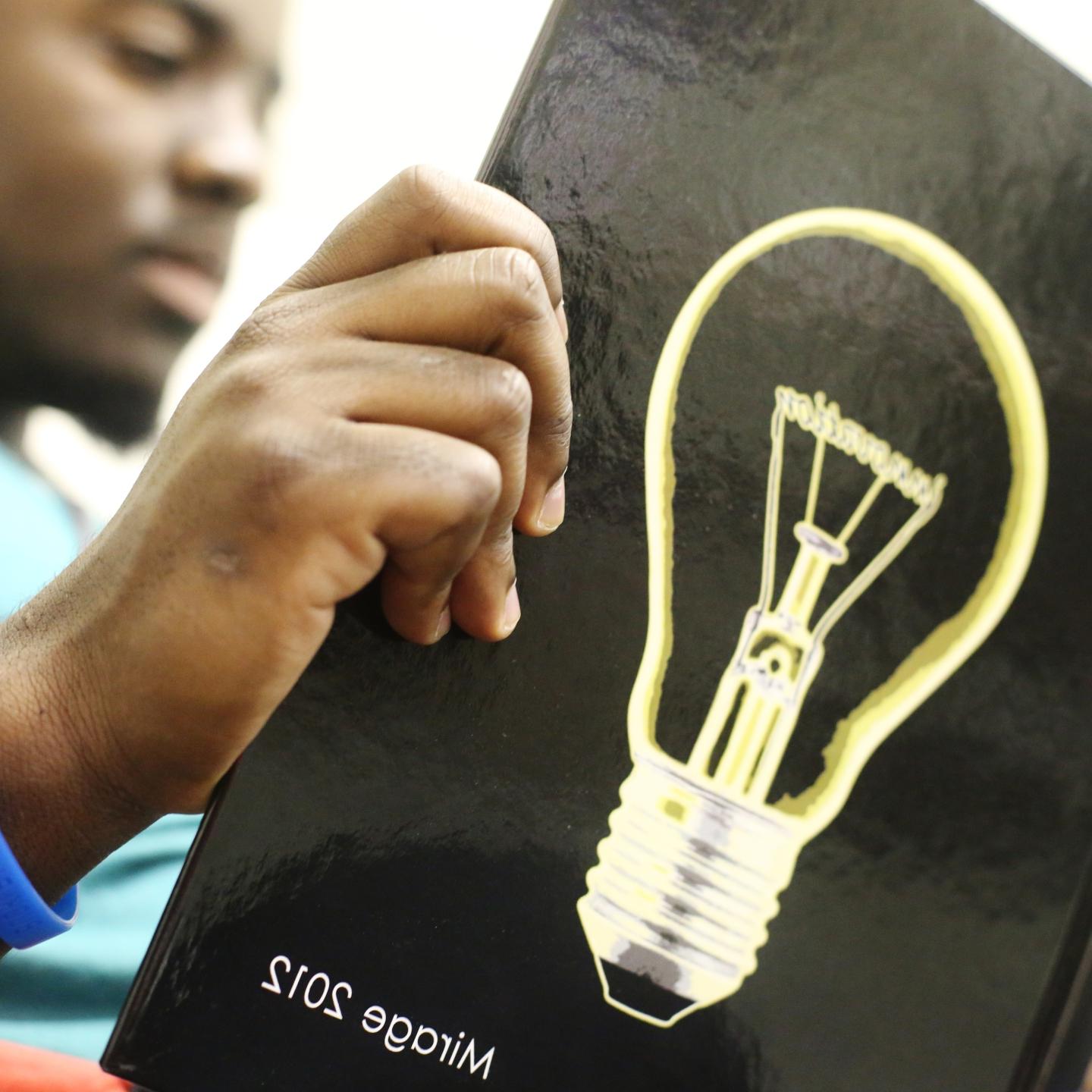 a student reads the 2012 Mirage with a lightbulb on the cover