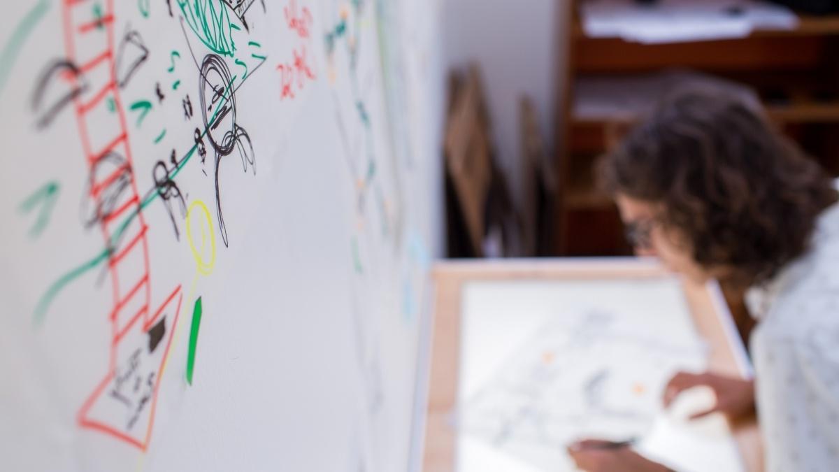 student drawing on a light box with a white board in the background