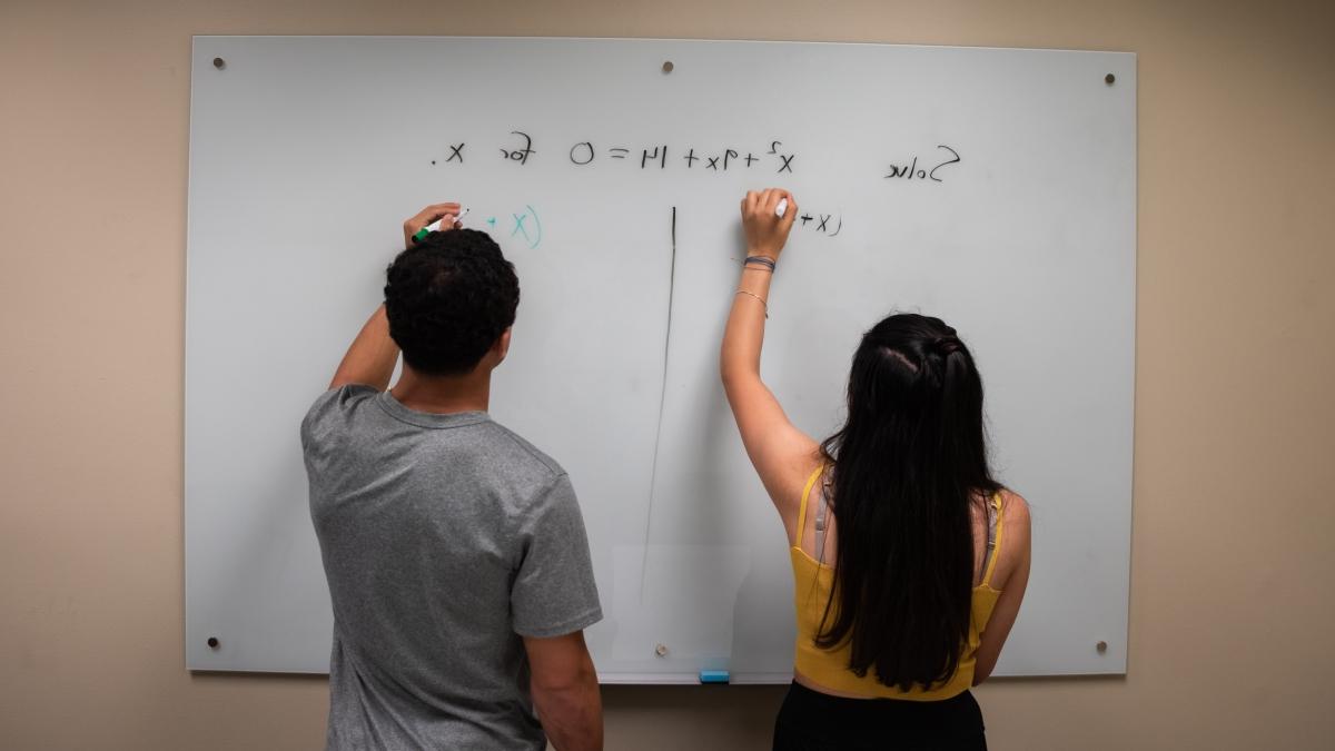 Two trinity students brainstorming on a whiteboard